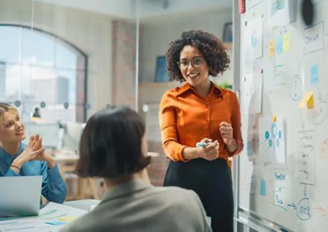 Three marketing professionals discussing a marketing plan on a whiteboard