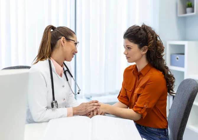 Nurse or Doctor holding hand of woman in clinic office