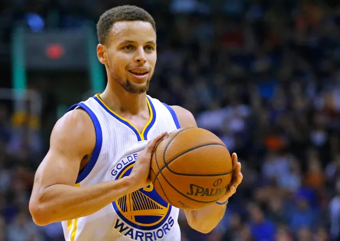 Steph Curry holding a basketball with a smile on his face.