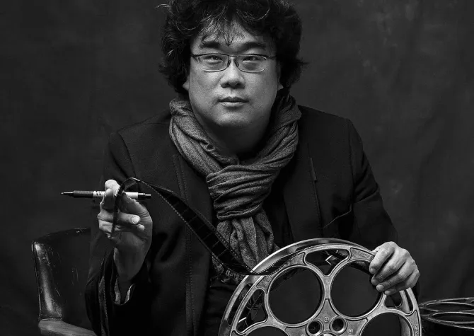 Joon-Ho staring straight at camera holding film reel.