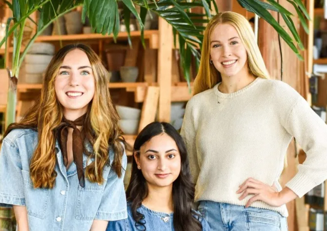 Three women smiling confidently at camera.