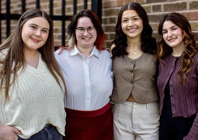 Four women smiling confidently at camera.