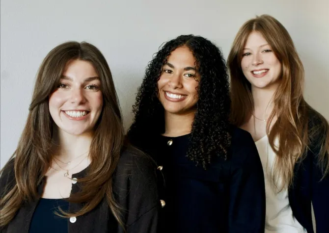 Three women smiling confidently at camera.