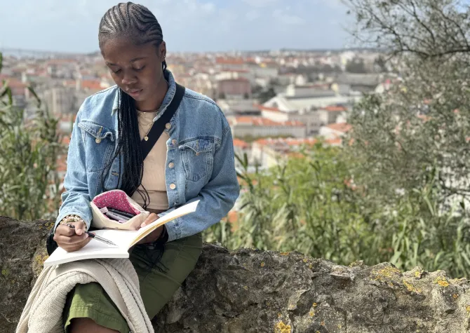 Student studying on top of stone ledge 