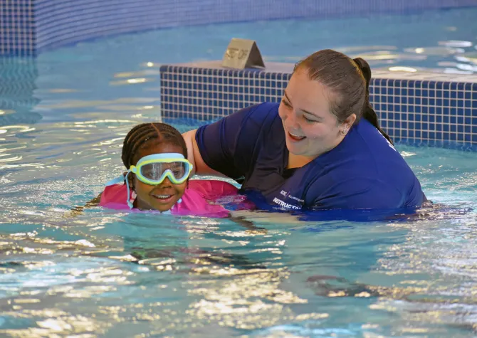 Swim lesson instructor guiding child participant