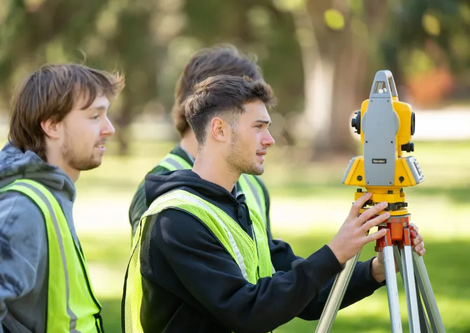 engineering students measure using surveying equipment
