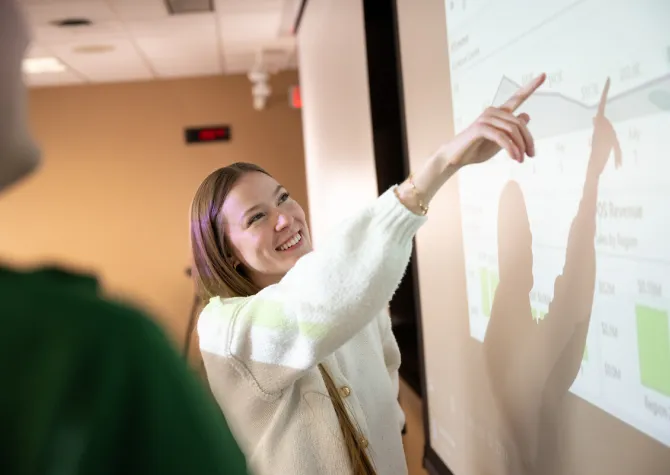 students discuss findings on the screen in a business class