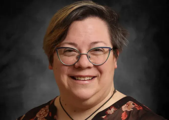 A woman with glasses smiles for a headshot