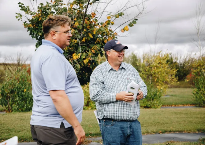 Two natural resource professionals learn about new species planted in a windbreak.