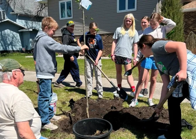 Students plant a tree in the boulevard.