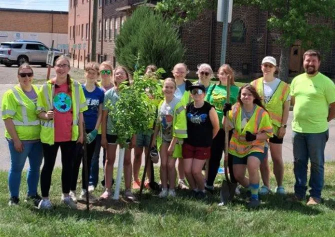 A group of Girl Scouts help plant trees.