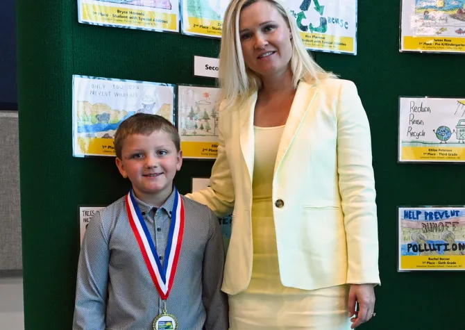 A young boy wearing a medallion poses for a photo with the ND First Lady.