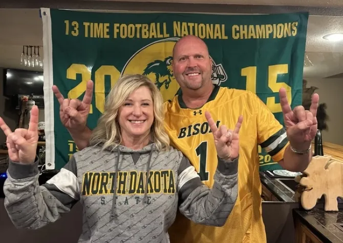 A man and a woman wear NDSU gear and smile