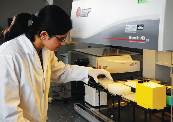Student researcher working in lab with lab equipment.