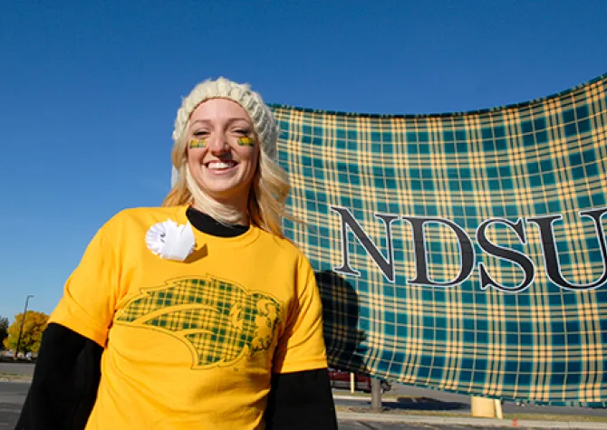 Student wearing NDSU tartan while smiling confidently at camera.