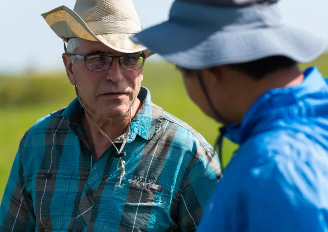 Dr. Otte talking to a research student in a green grassy field.