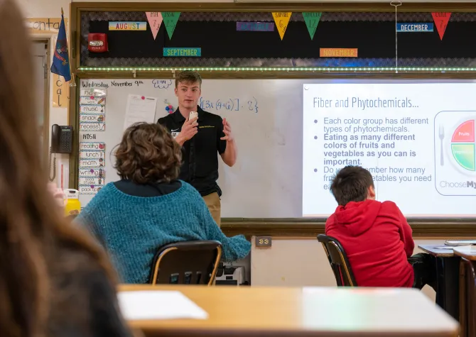 Student teacher standing at front of the classroom teaching younger students in a health class