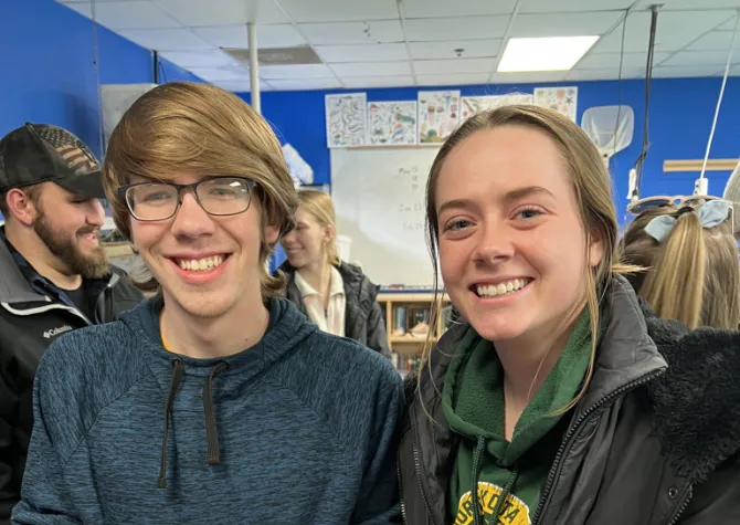 Two students smiling confidently at camera while holding sea urchins.