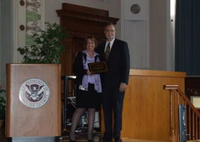 Two people holding an award while smiling at camera. 