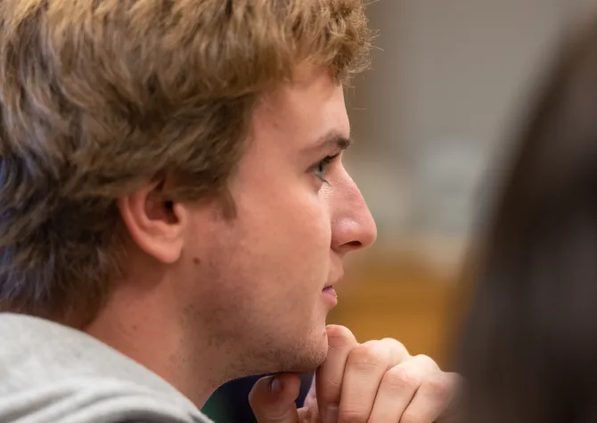 Student sitting in class, resting chin on hand