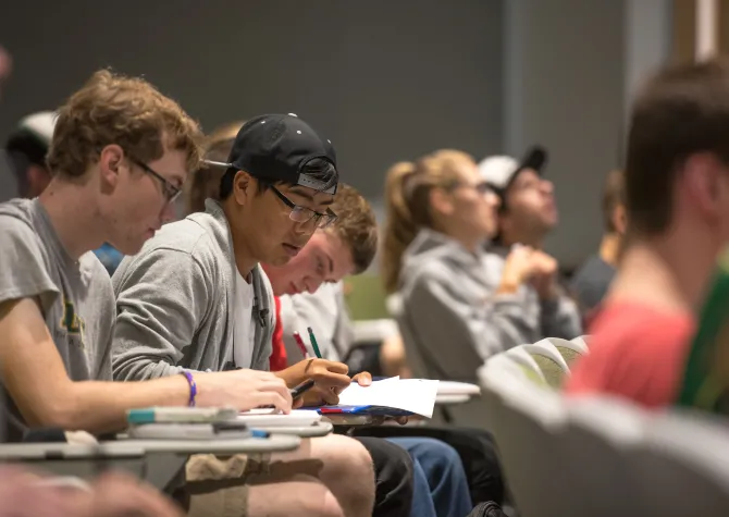 Students sitting at desks working with pencil and paper. 