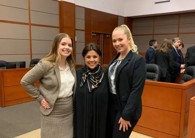 Three women standing and smiling conifdently at the camera. 
