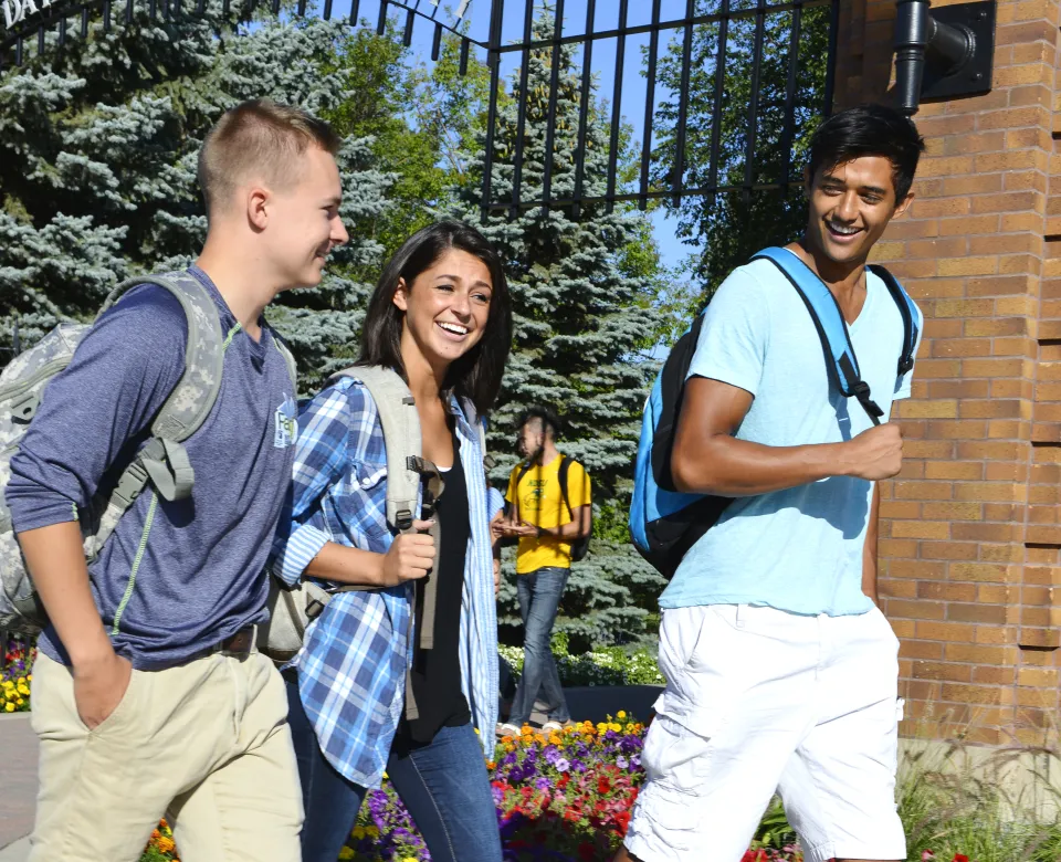 Three students walking past campus gate.