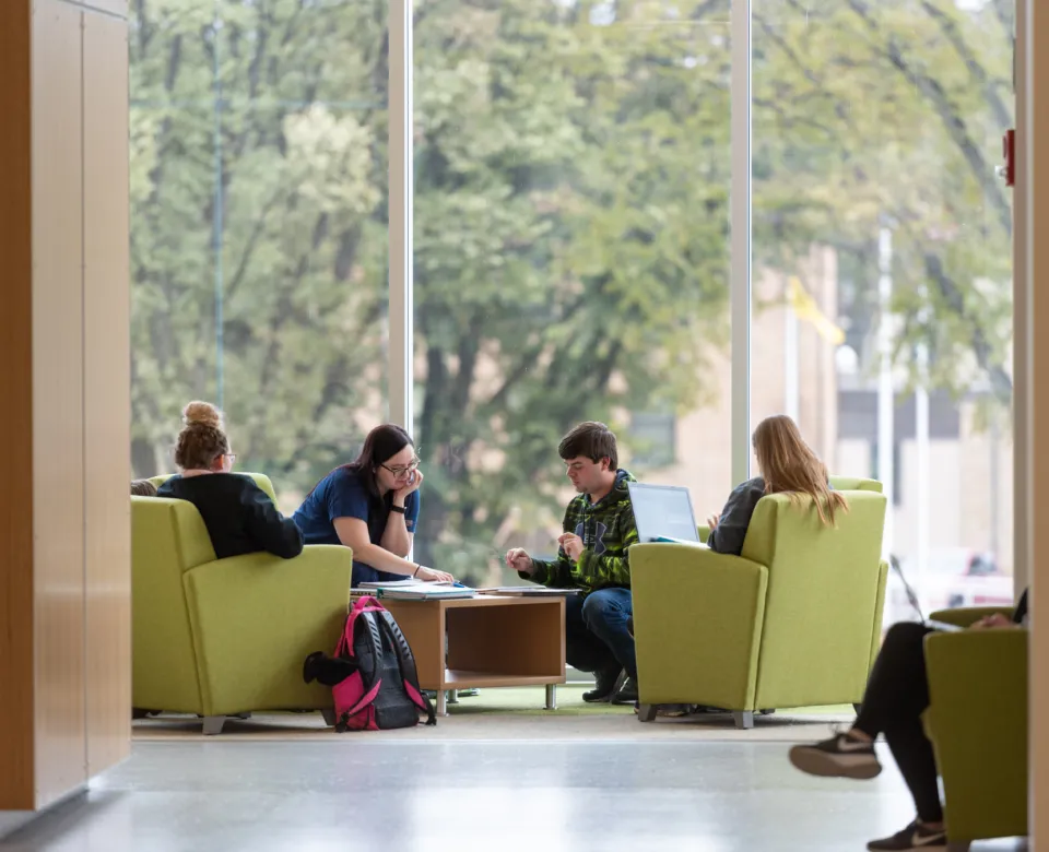 Four students reviewing project in A.G. Hill atrium study space.