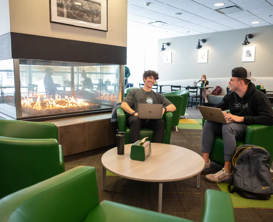 two students lounging next to a fire in a dining center