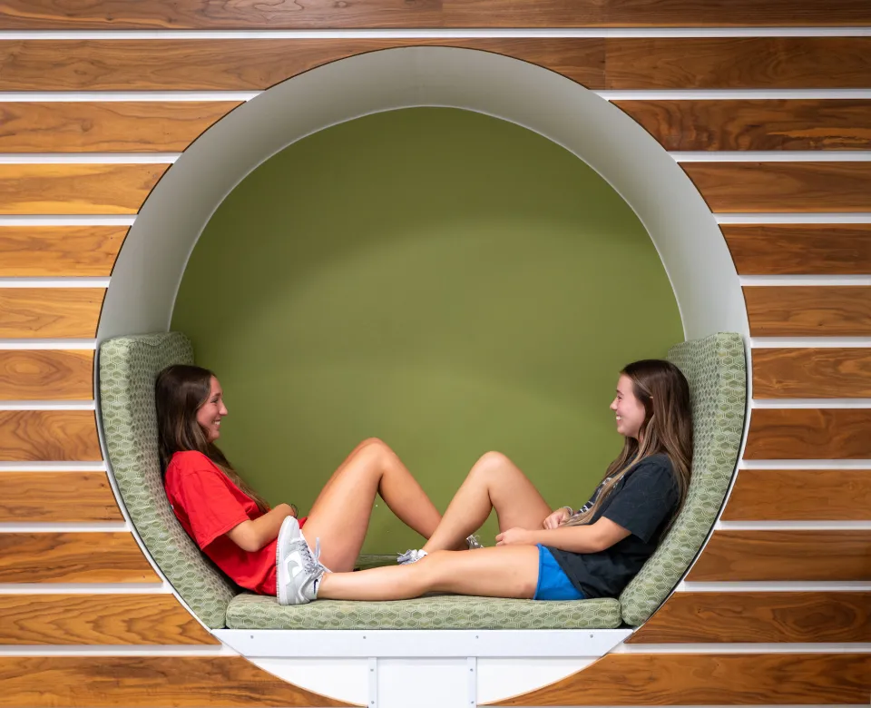 Two students lounging in a circular cubby in Cater Hall