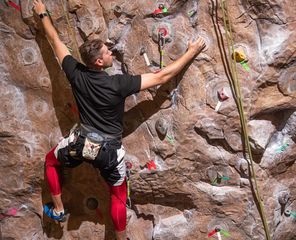student on rock climbing wall at Wallman Wellness Center