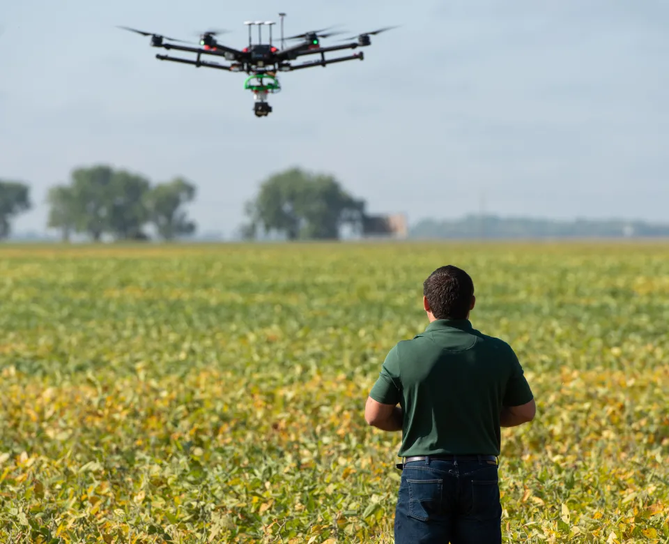 faculty member flies a drone over a field