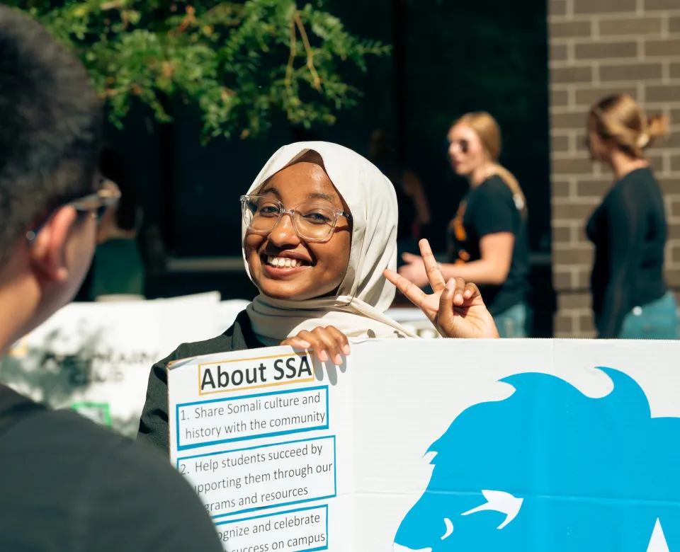 member of the Somali Student Association holding a sign about the club at the Student Involvement Expo