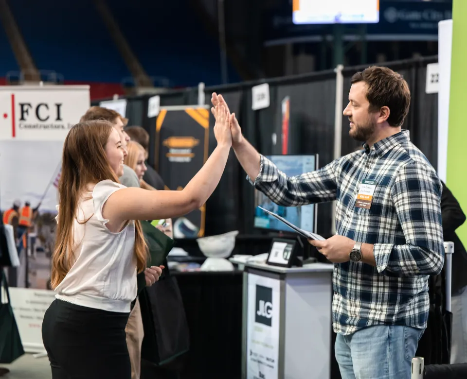 students high-fiving a business respresentative at the Fall Career Expo