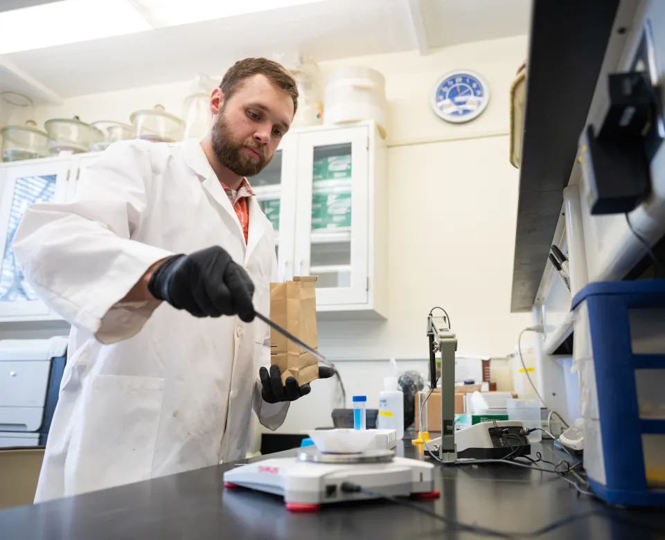 student weighing samples of dirt on a scale