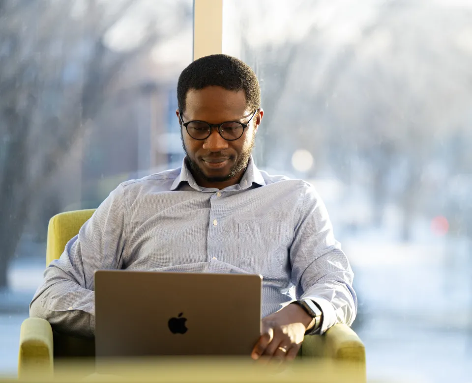student working on a laptop in front of a window