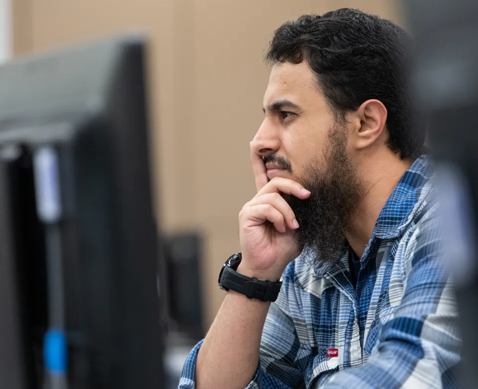 graduate student looking thoughtfully at a computer