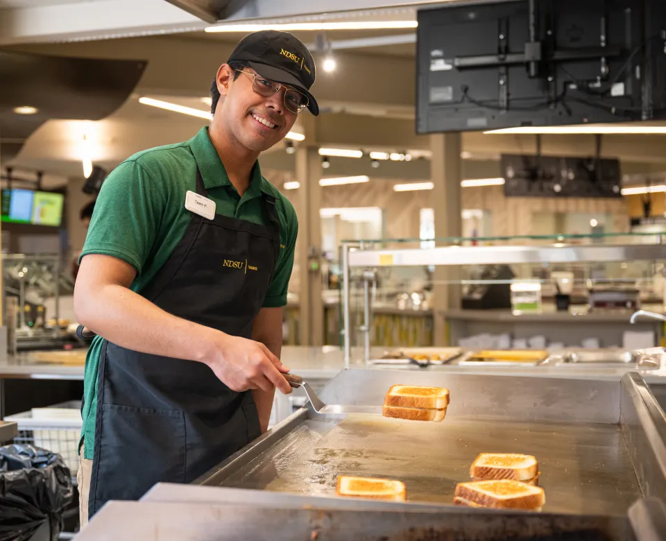 Student working in NDSU Dining making grilled cheese sandwiches