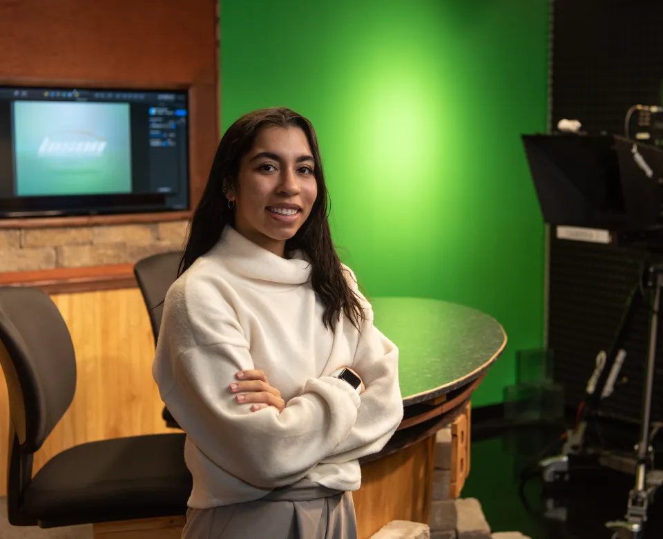 Student standing with arms crossed looking confidently into the camera