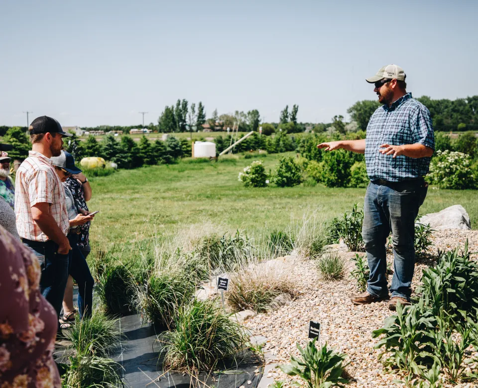 A man stands atop a rain garden and speaks to a group of people