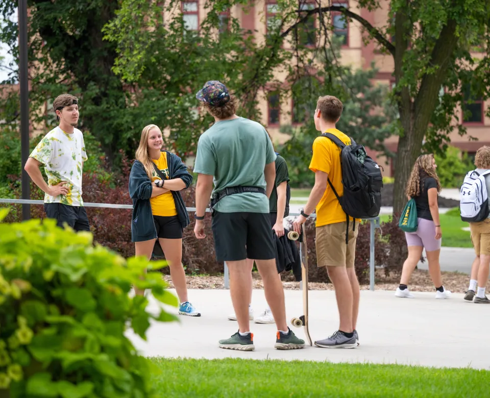 Students standing outside on the NDSU campus tlaking and hanging out