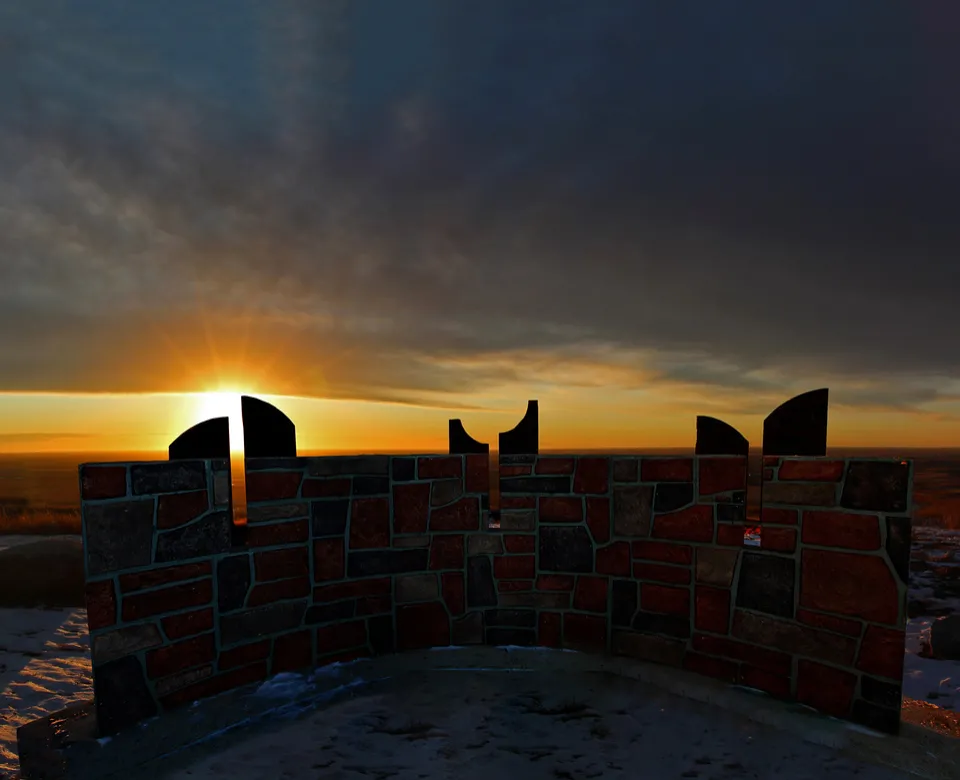 A silouette of a stone structure is iluminated by the sun