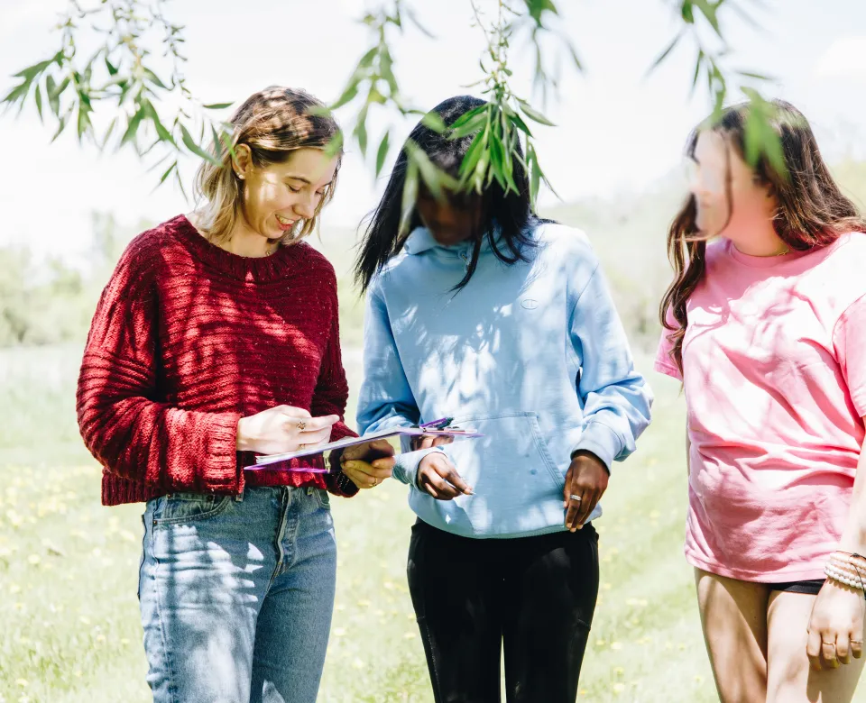 A young woman works on a worksheet with two younger girls