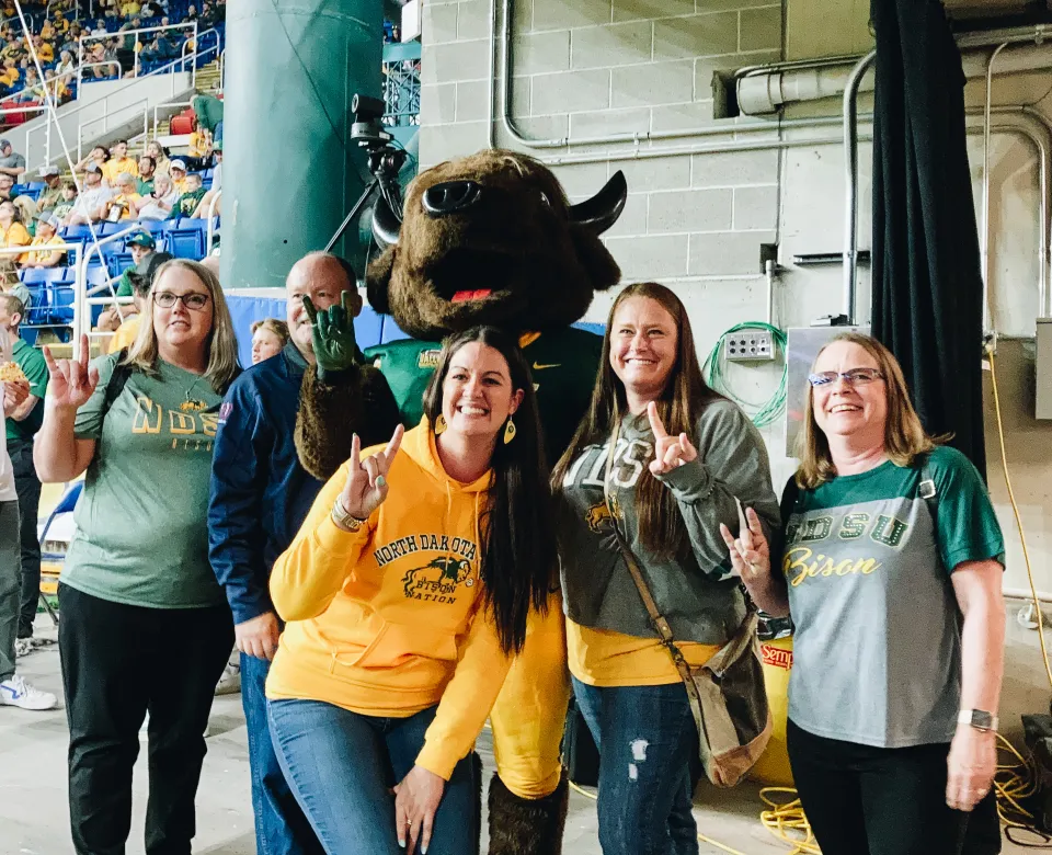 A group of women stand by a bison mascot
