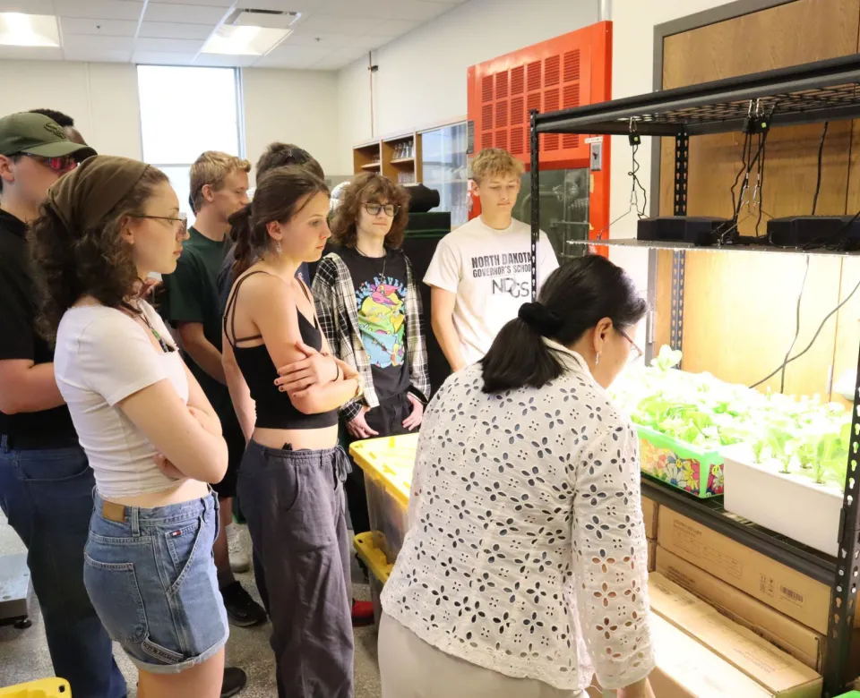 Professor Xinhua Jia shows an experimental crop of plants to a group students