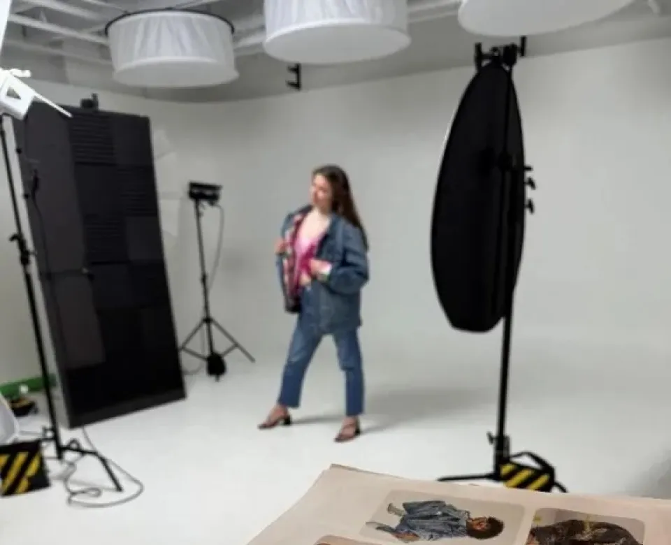 Student posing in front of camera wearing jeans and a jean jacket.