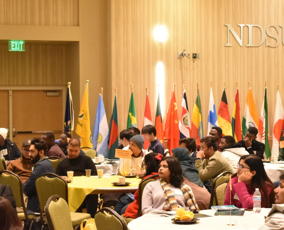 Students sitting at attention with flags in the background