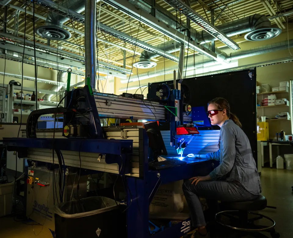 Student wearing protective eyewear while working at computer in a lab setting.