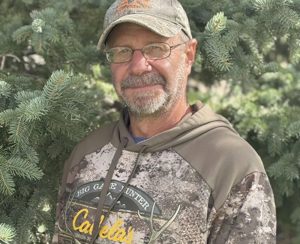A man in a ballcap and glasses grinning