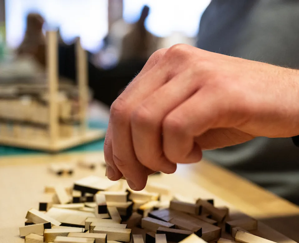 Hand working with small pieces of wood.